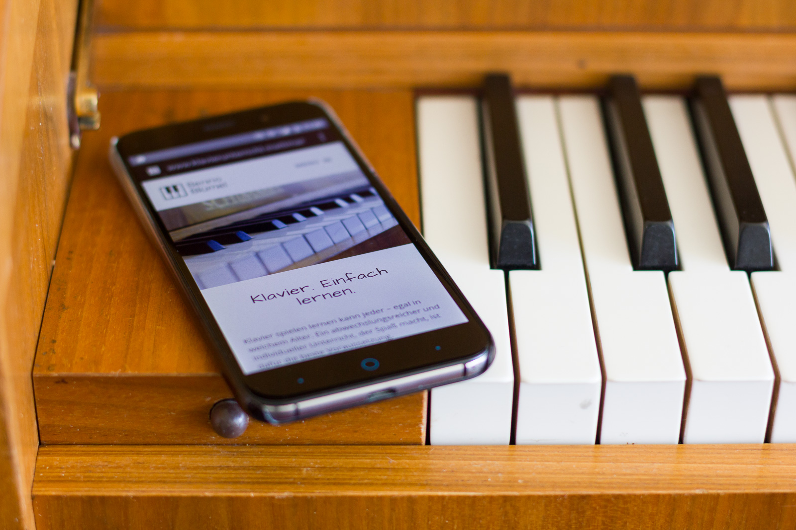 Kontakt & Anfahrt: Handy mit Website neben Klaviertasten